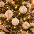 White and gold velvet Christmas ball ornaments hanging on a lit Christmas tree with gold ribbon and pinecones