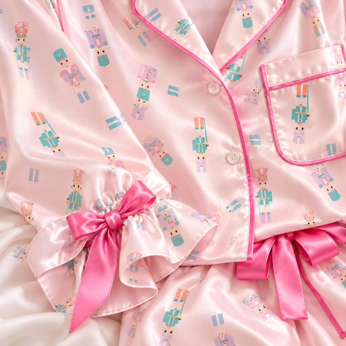 Close-up of pastel nutcracker print pink satin with pink piping and satin bow cuff