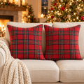 Set of 2 red tartan plaid Christmas throw pillow covers on a cream sofa with a knit throw and lit Christmas tree