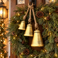 Three vintage gold Christmas bells with jute rope hanging on a pine wreath on a front door