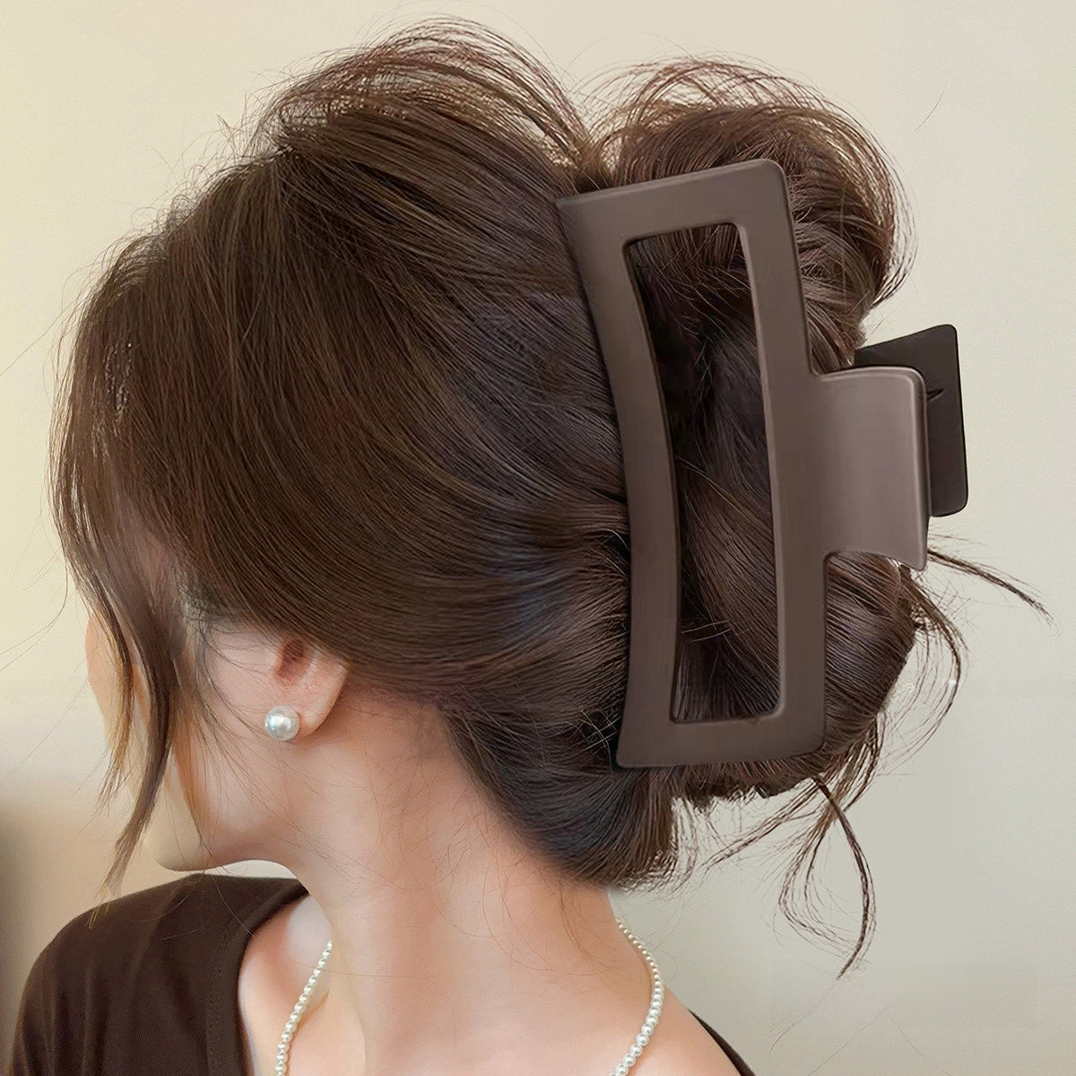 Matte dark coffee brown square claw clip holding long hair