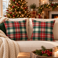 Classic red, green and white plaid Christmas pillow covers on a cream sofa by a Christmas tree