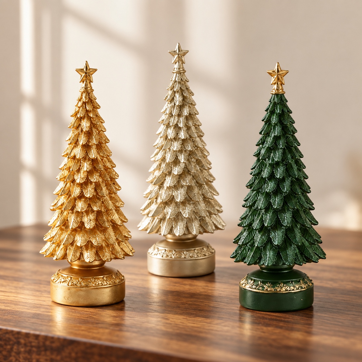 Set of 3 resin tabletop Christmas trees in gold, light gold and green on a wooden table