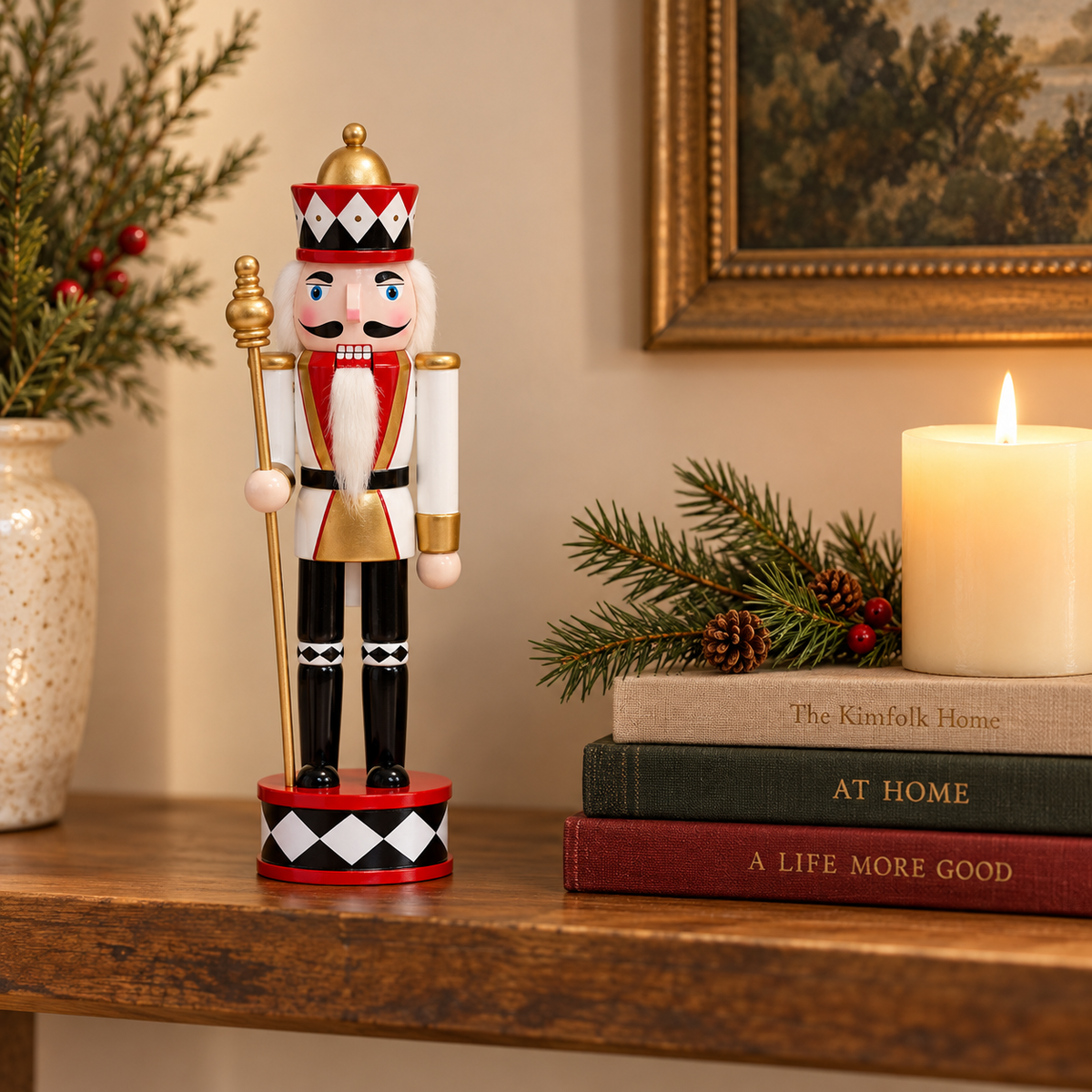 Nutcracker king in white and gold uniform on a wooden shelf beside books and a candle to show its 12 inch size