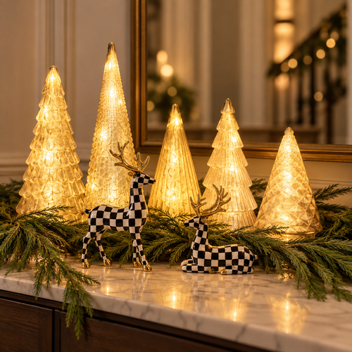 Gold lighted tabletop trees with black and white checkered deer and pine garland on a marble entry table
