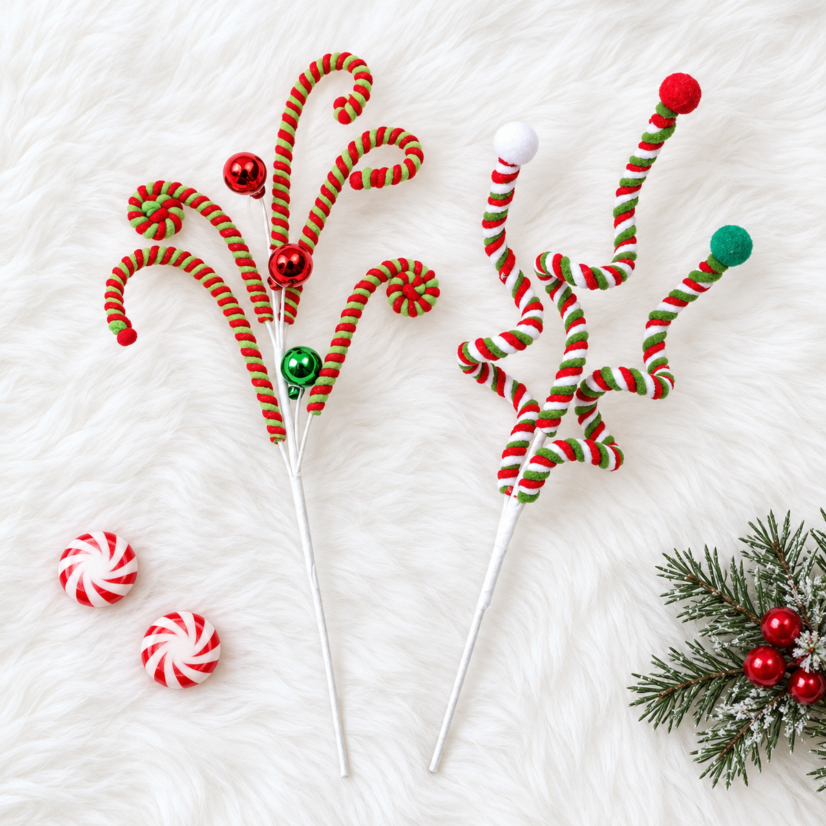 Curly candy cane spray and twisted pom-pom spray Christmas picks side by side on white faux fur